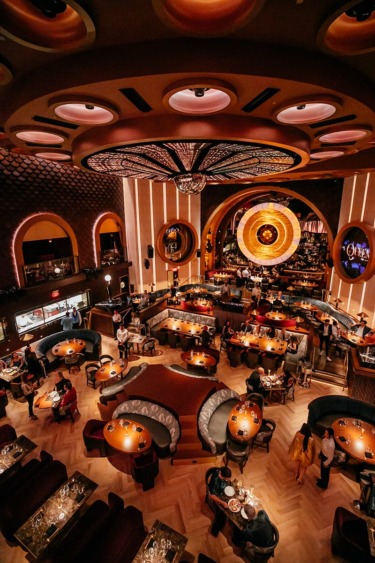 Luxurious restaurant interior with elegant lighting, round booths, and patrons dining, creating a warm and inviting atmosphere.