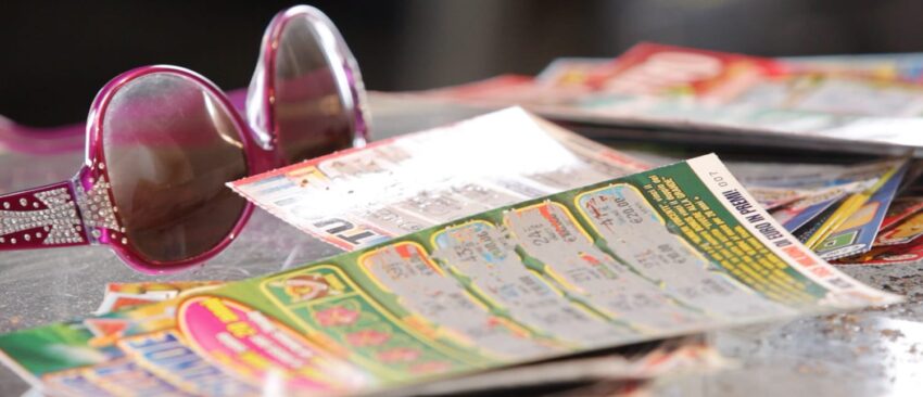 Sunglasses beside a pile of colorful lottery scratch cards on a table.