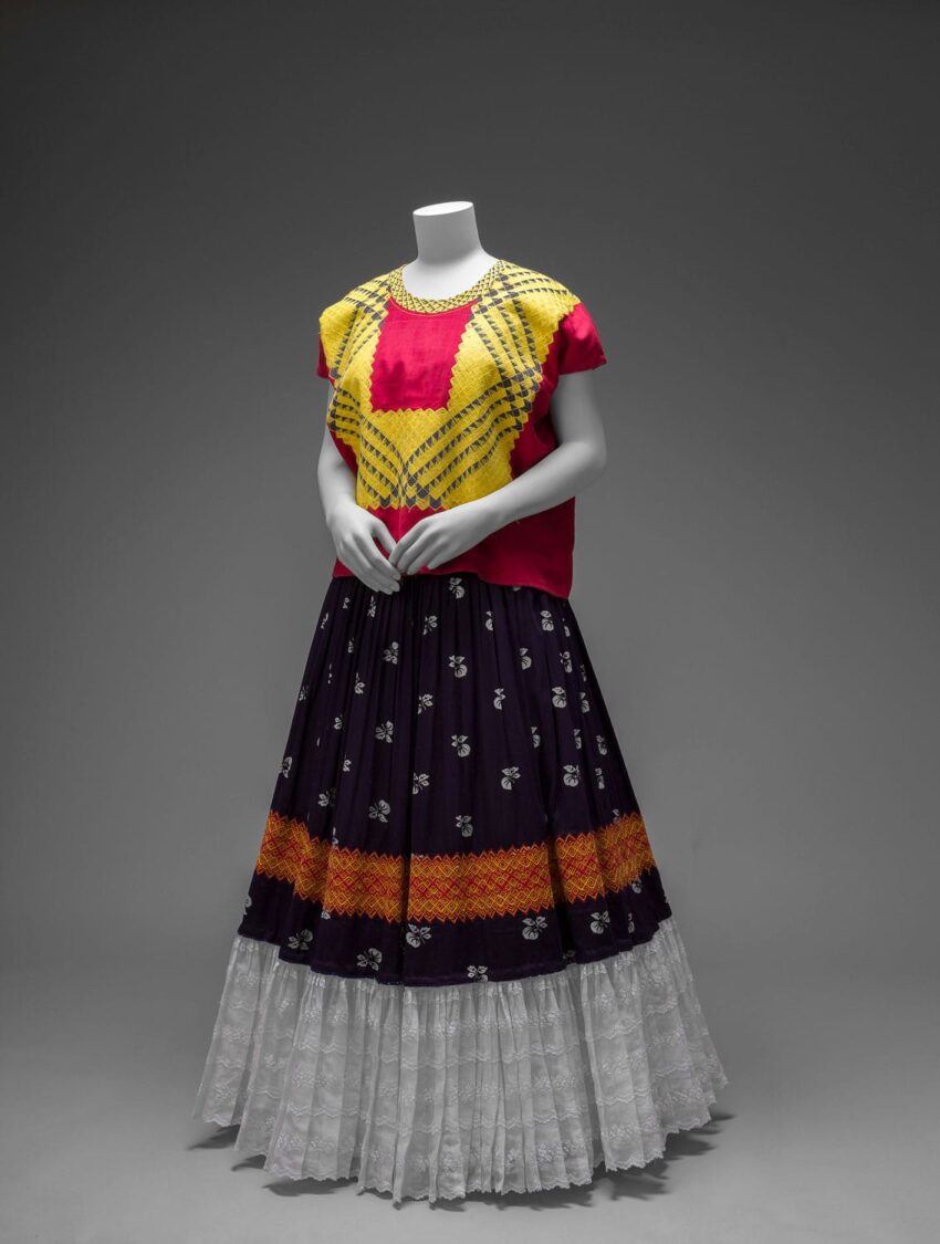 Mannequin wearing a colorful traditional outfit with a bright yellow and red top and a patterned long skirt.