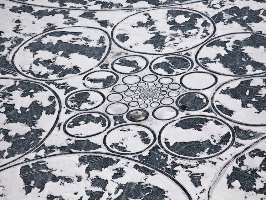 Aerial view of snow-covered circular patterns on a winter landscape, resembling a giant abstract flower.