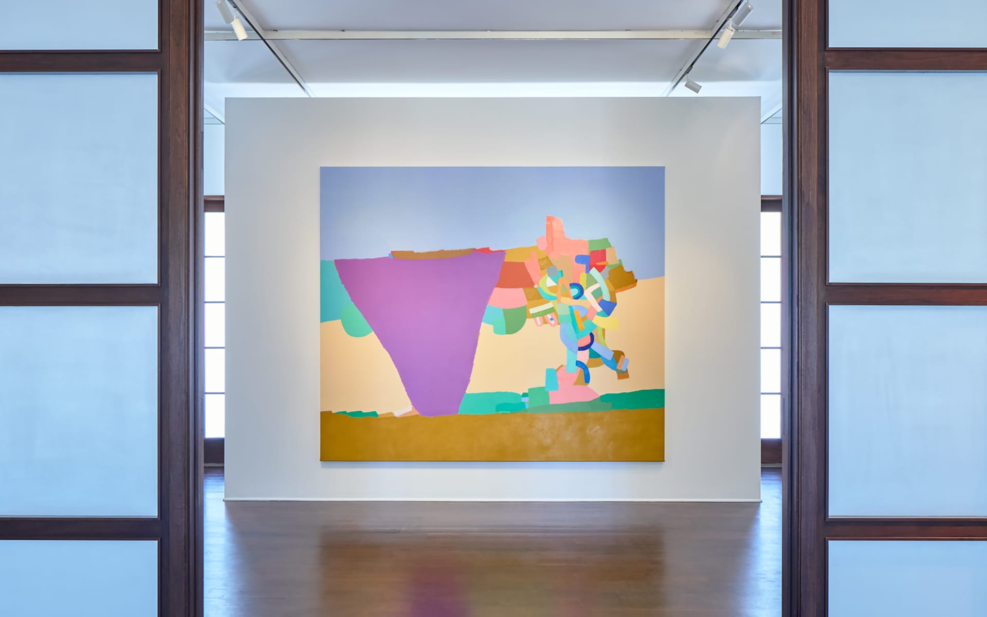 Colorful abstract painting displayed in a bright gallery space with wooden floors and framed walls.