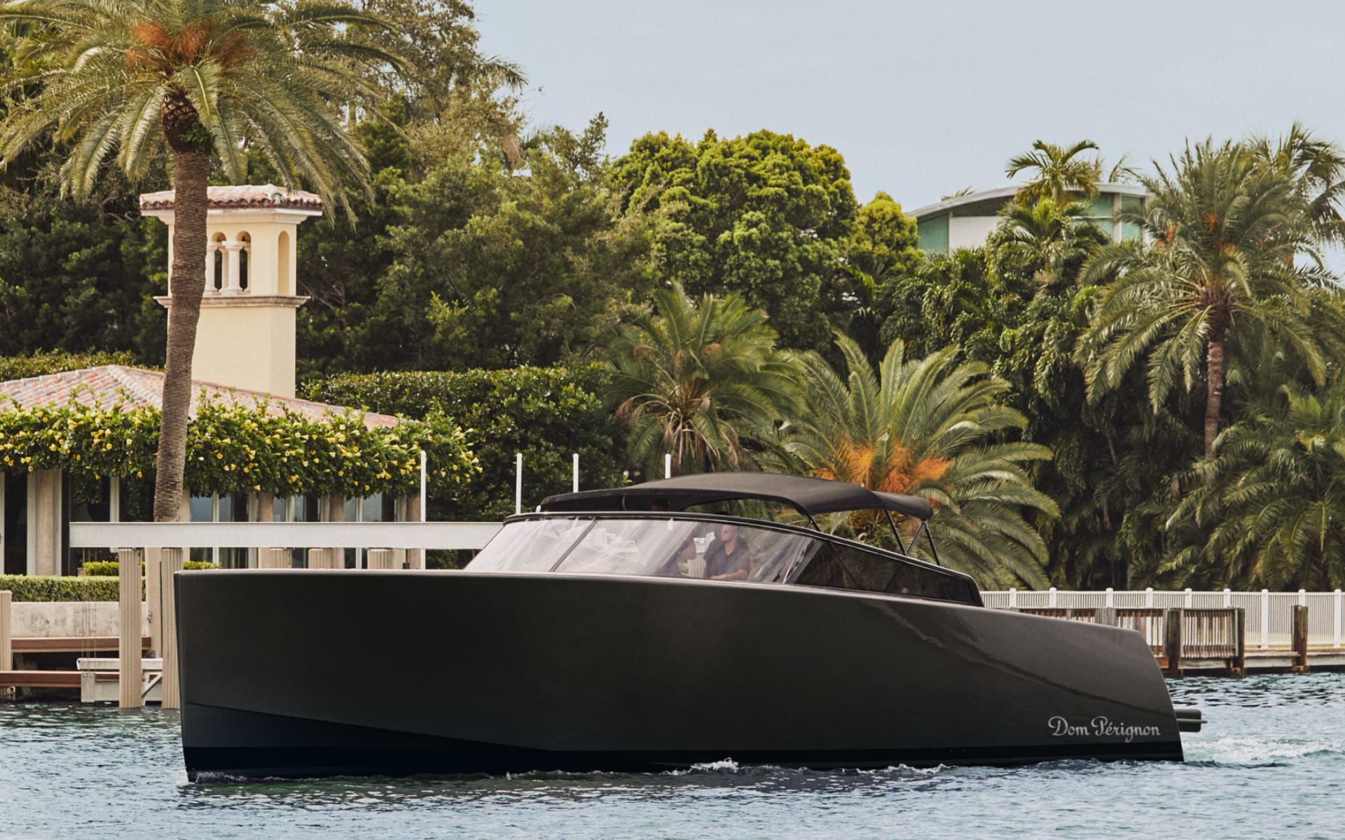 modern black yacht cruising near a dock surrounded by palm trees