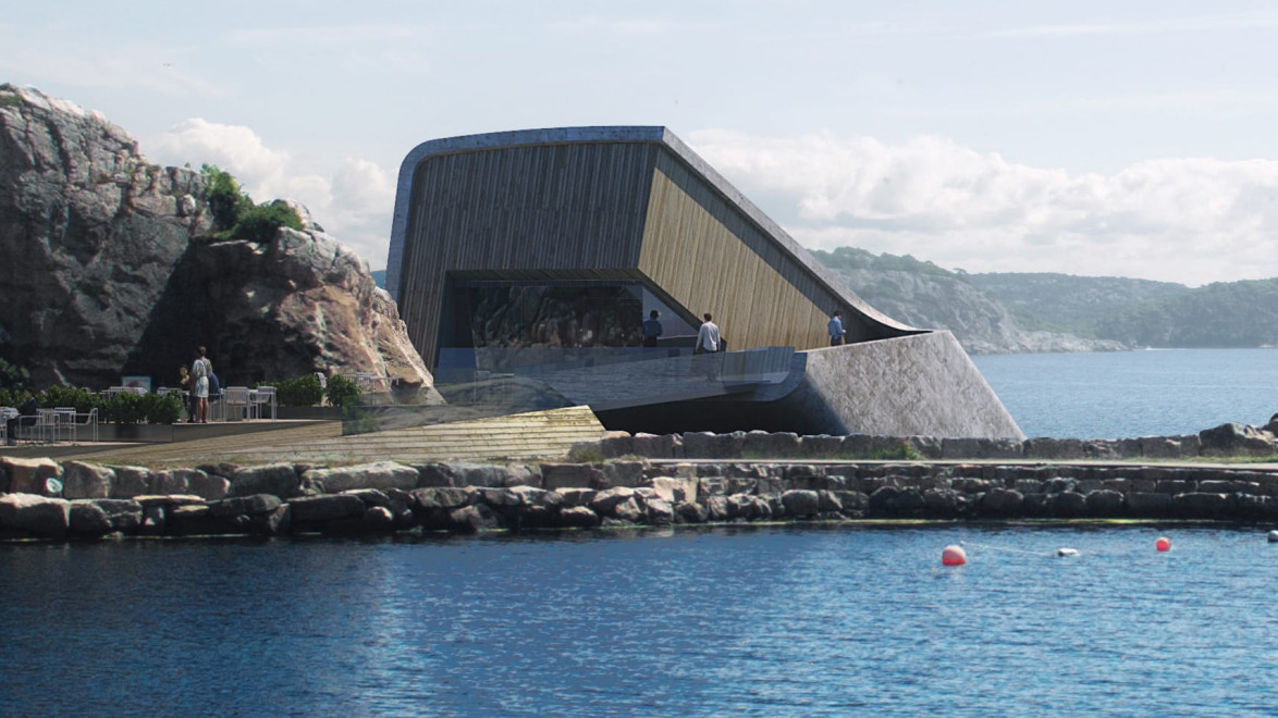 Modern building emerging from cliffs by a serene waterfront, featuring large windows and surrounded by rocky landscape.