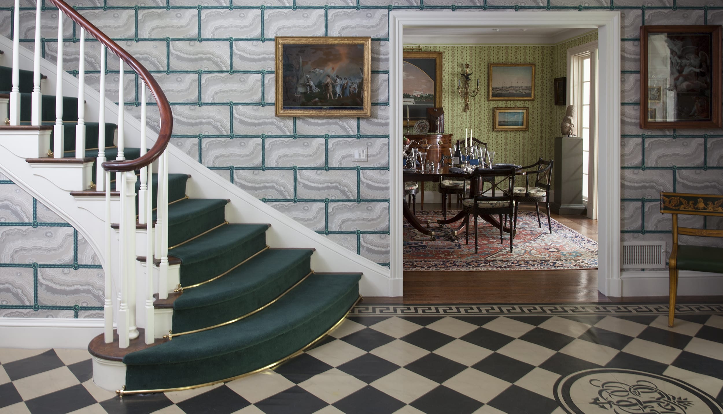 Elegant interior with green carpeted spiral staircase, decorative wall panels, and a dining room view with classic furnishings.