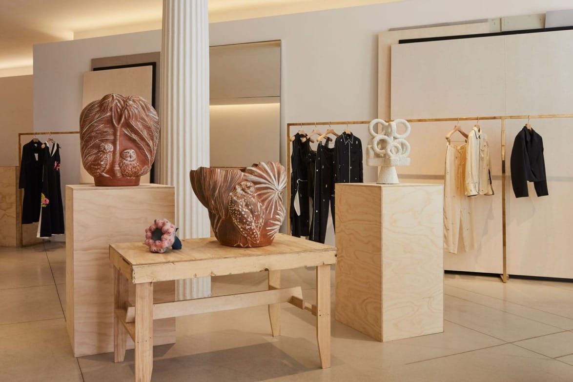 A boutique showcasing unique ceramic sculptures and elegant clothing on racks and display tables.