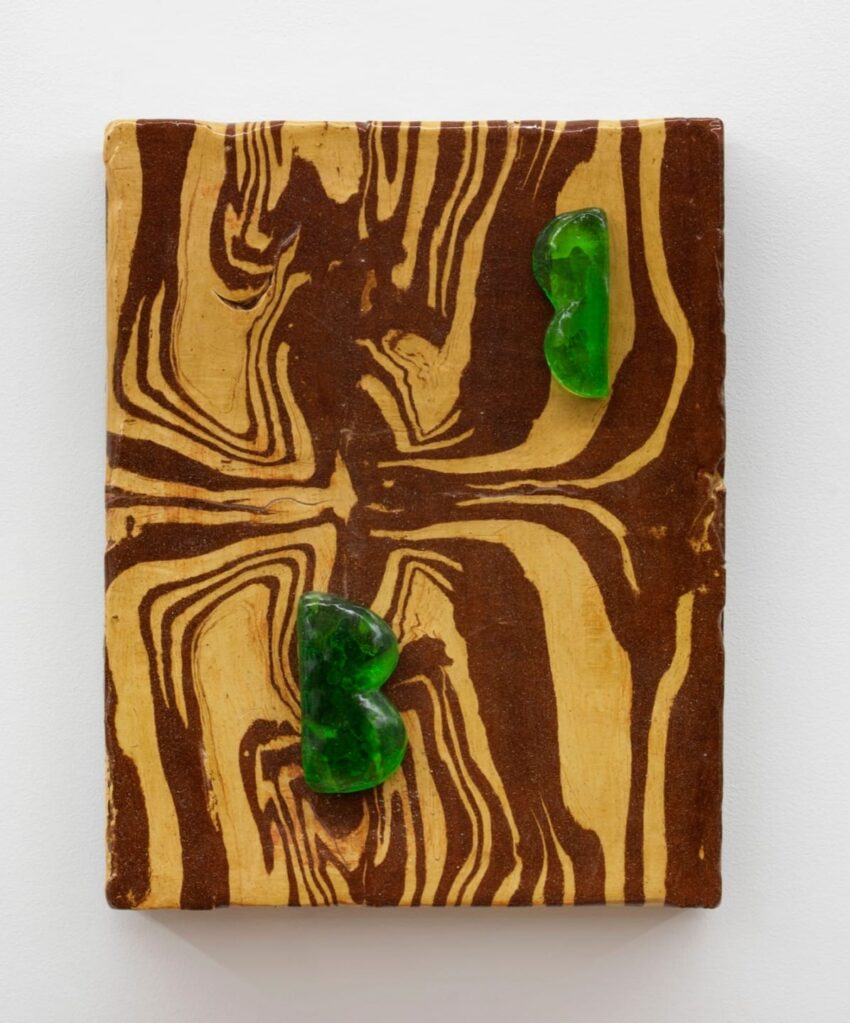 Wood grain canvas with two green heart-shaped objects placed symmetrically, creating an earthy and artistic display.