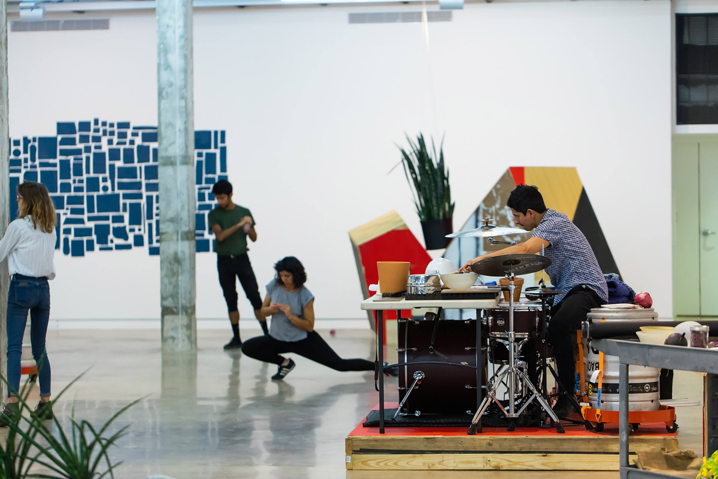 Artistic performance in a modern gallery with musicians and dancers in motion, surrounded by abstract displays and decor.