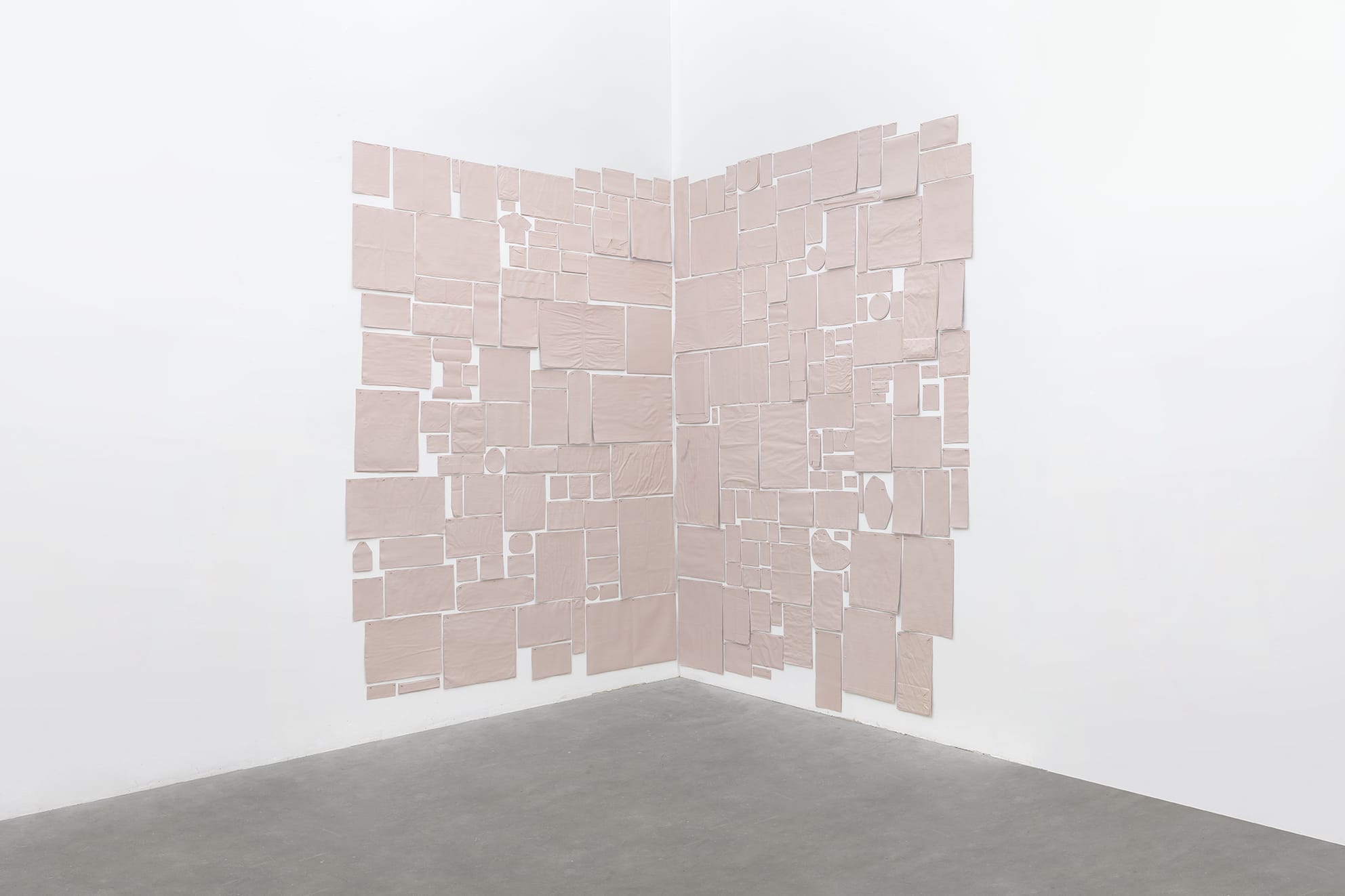 Abstract art installation with beige rectangular panels arranged on two white walls meeting at a corner, minimalistic style.