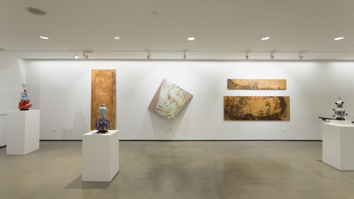 Contemporary art gallery with abstract paintings and intricate sculptures on white pedestals.