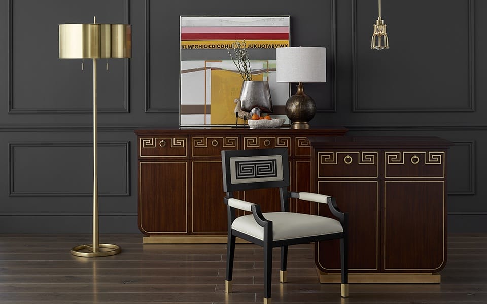 Elegant living room with dark paneled walls, gold accents, a wooden sideboard, modern lamp, and a decorative armchair.