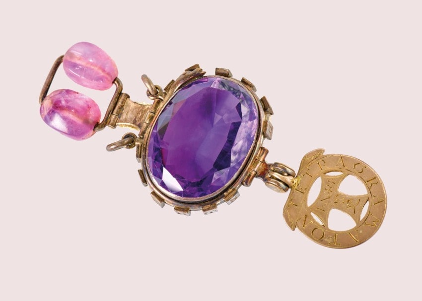 Antique gold keychain with a large purple gemstone and two pink beads, featuring an intricate circular metal charm.