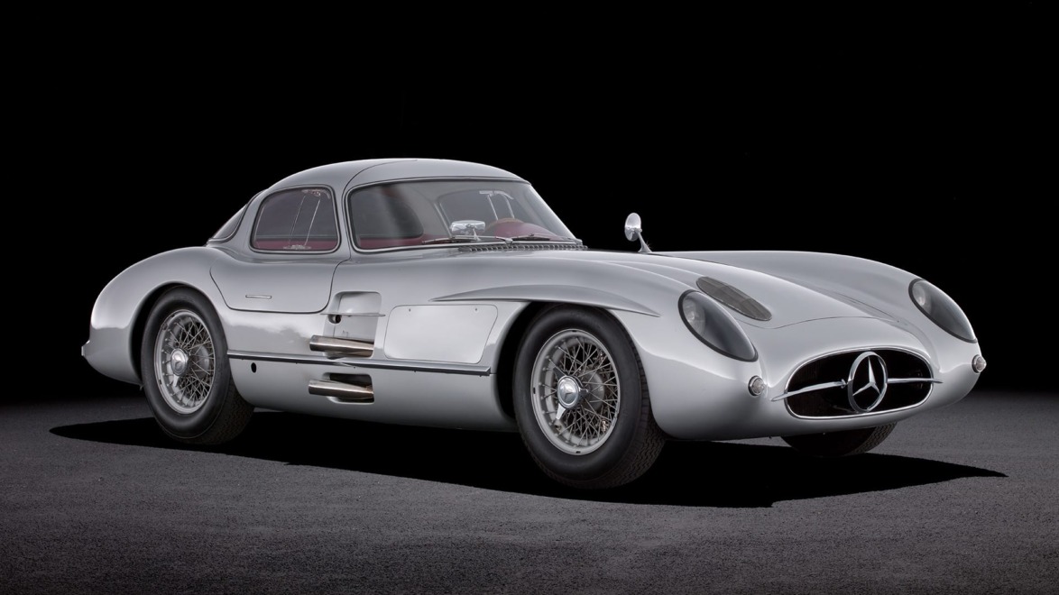 Vintage silver sports car displayed on a dark background, showcasing sleek curves and classic design features