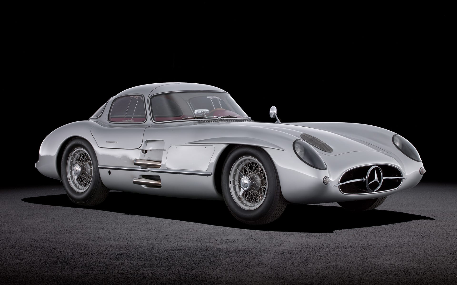 Vintage silver sports car displayed on a dark background, showcasing sleek curves and classic design features