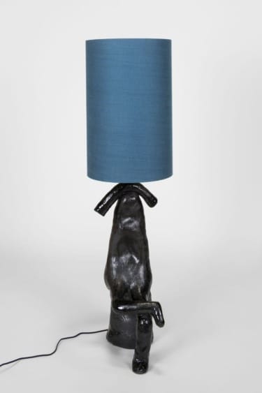 Unique lamp with a sculpted dark base resembling a dog sitting, topped with a cylindrical blue shade.