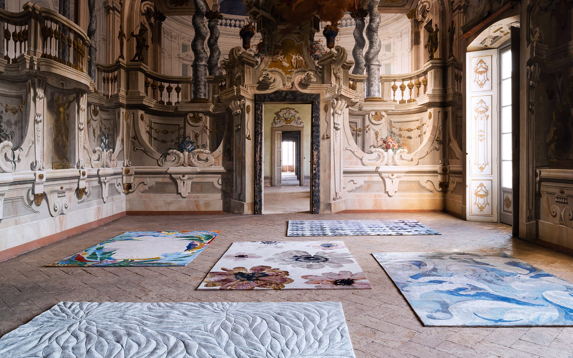 Ornate room with elaborate wall designs featuring four decorative rugs on a patterned tile floor.