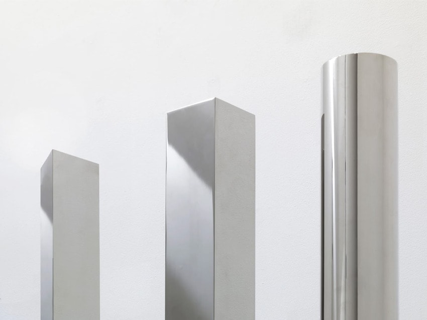 Three modern silver sculptures of varying heights with smooth surfaces against a plain white background.