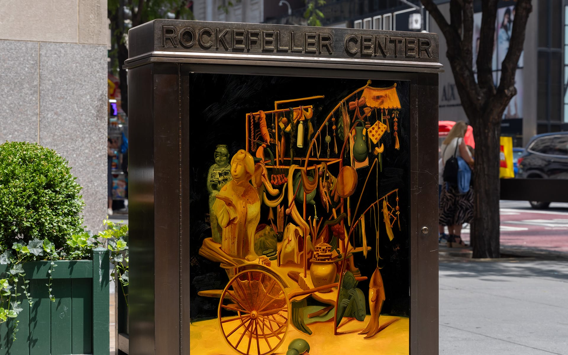 Artistic display in a glass case at Rockefeller Center showcasing various abstract objects and figures.
