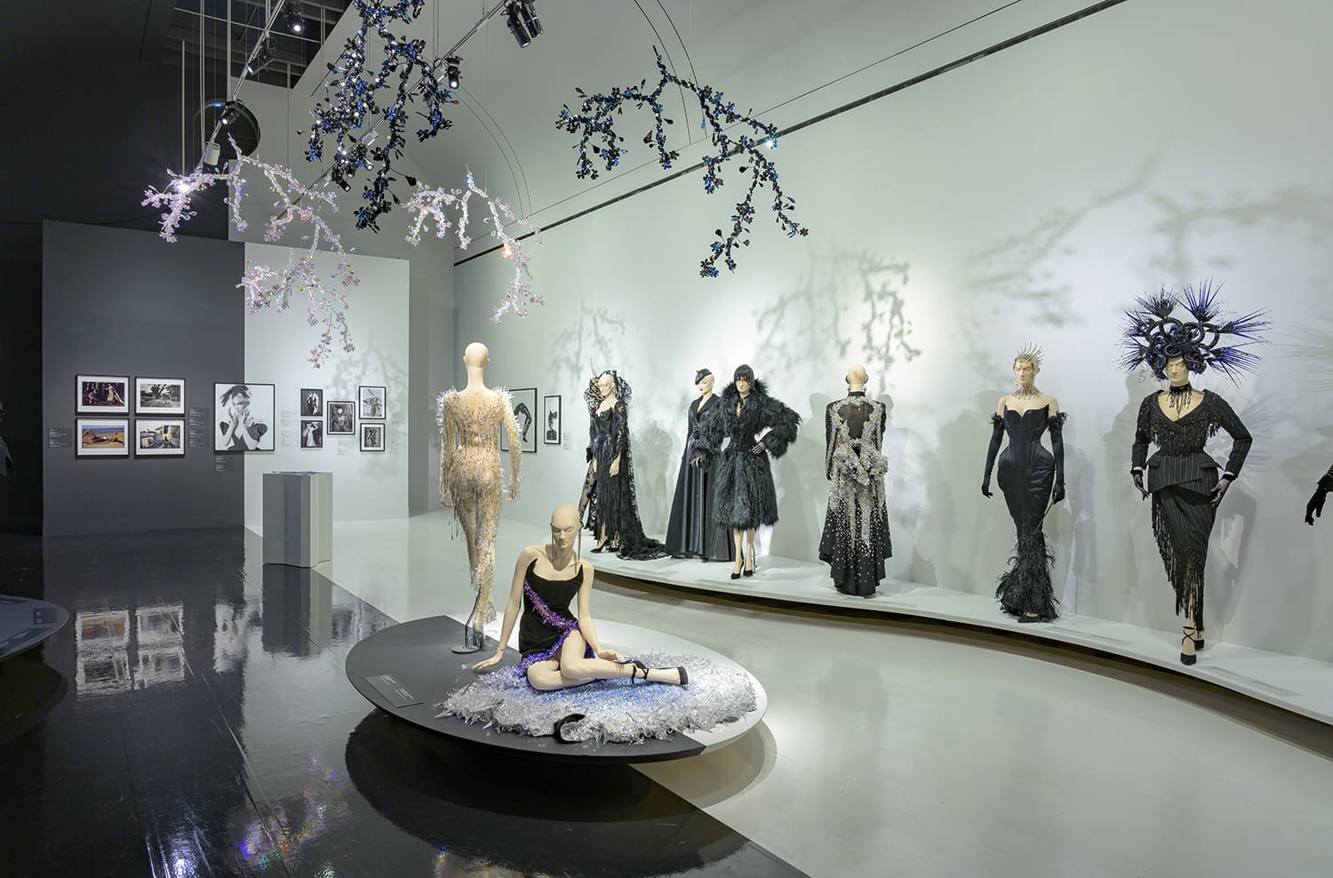 Fashion exhibit with mannequins wearing artistic black dresses in a modern gallery setting.