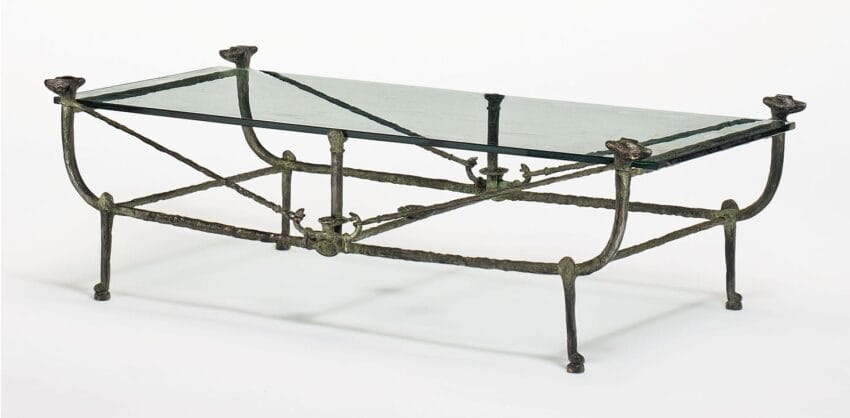 Glass top coffee table with ornate bronze metal frame and decorative design on a white background