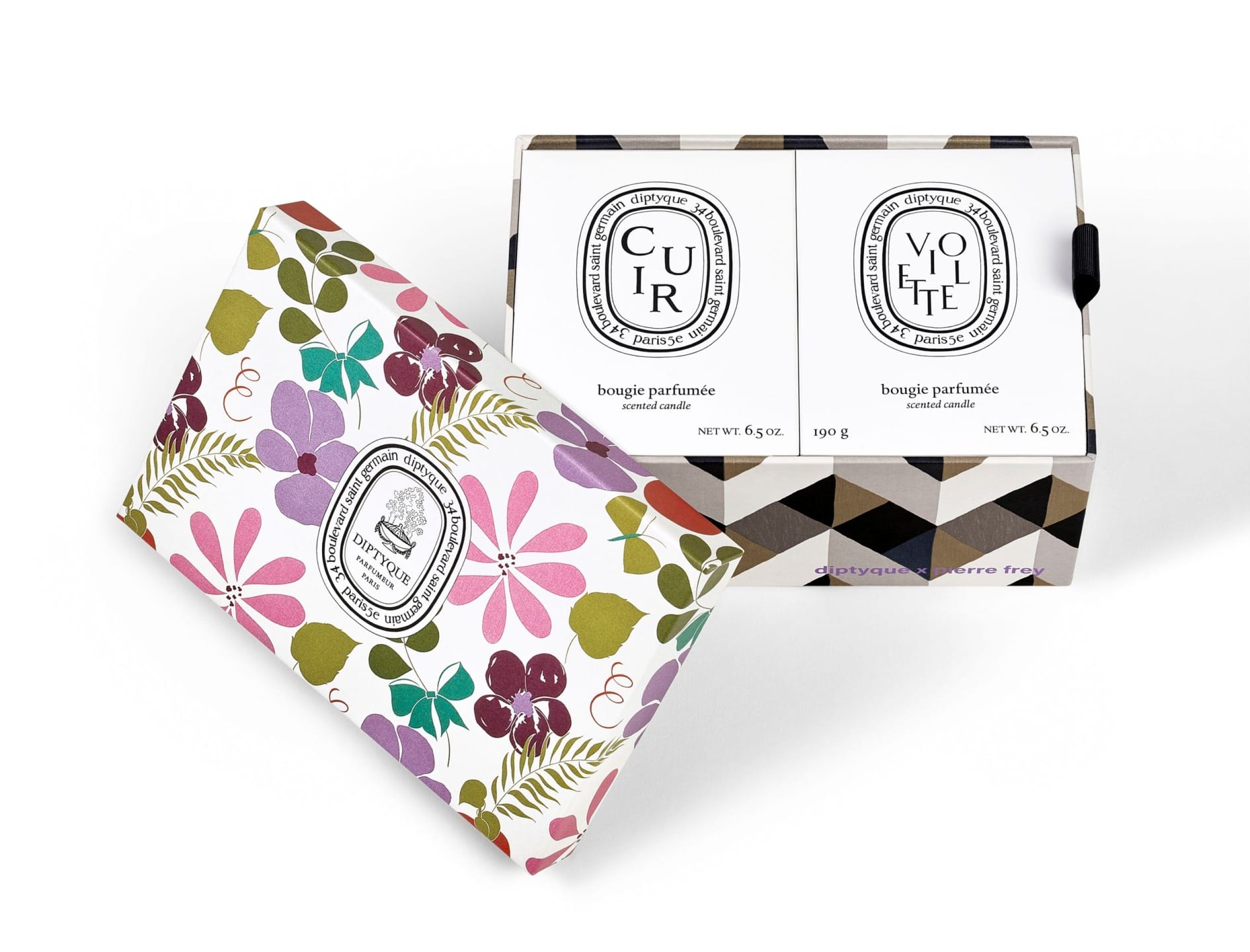 Colorful floral designed box with two Diptyque scented candles placed inside an open patterned package.