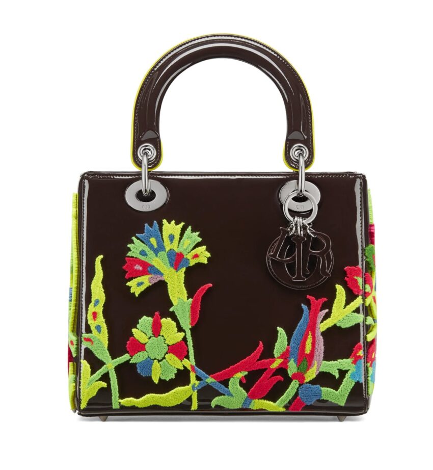 Brown handbag with colorful floral embroidery and a metal charm attached to the handle.