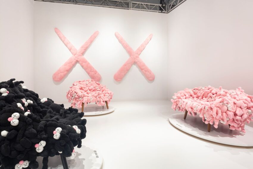 Art installation featuring plush black and pink sculptures resembling animals with embroidered crosses for eyes.