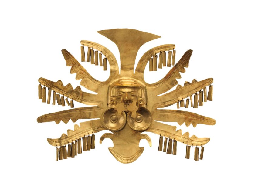 Pre-Columbian gold artifact with a sunburst design, decorative tassels, and intricate central face motif.