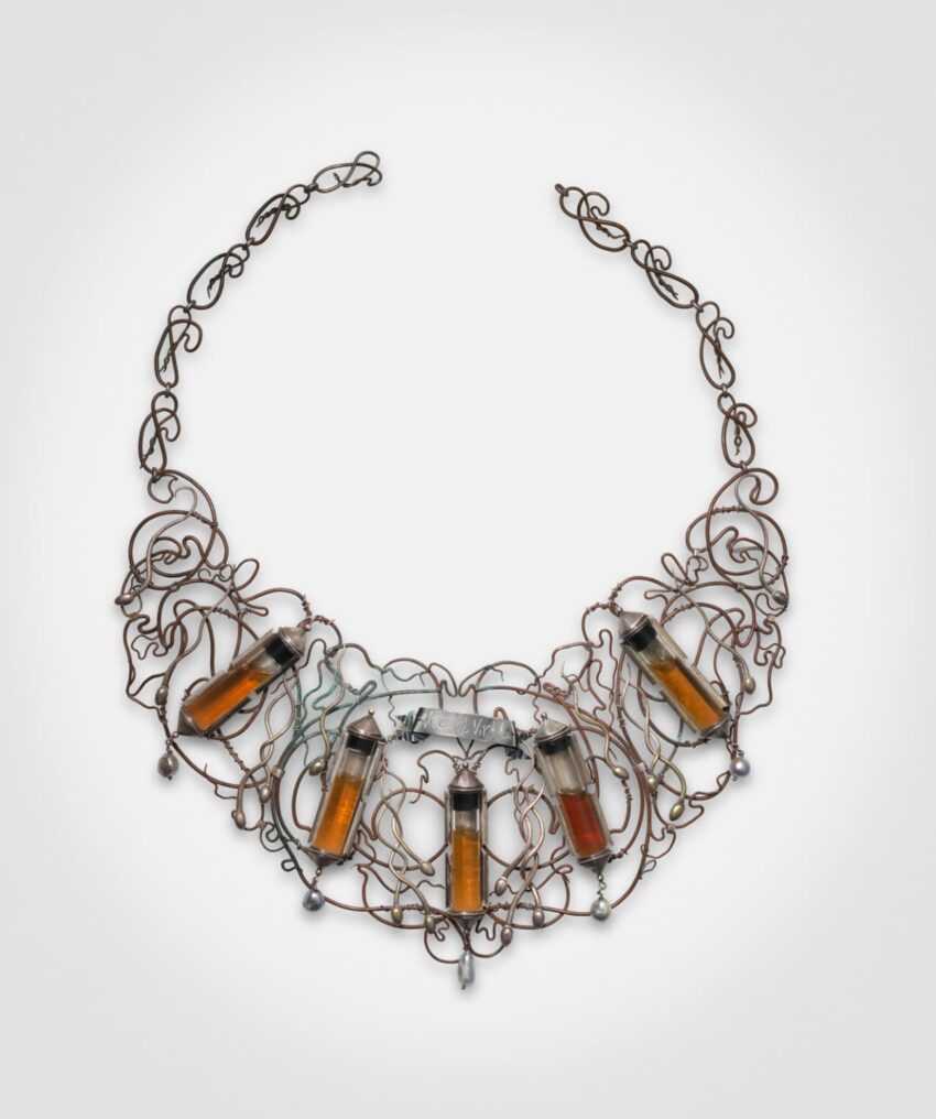 Intricate wire necklace with five small glass vial pendants filled with amber liquid.
