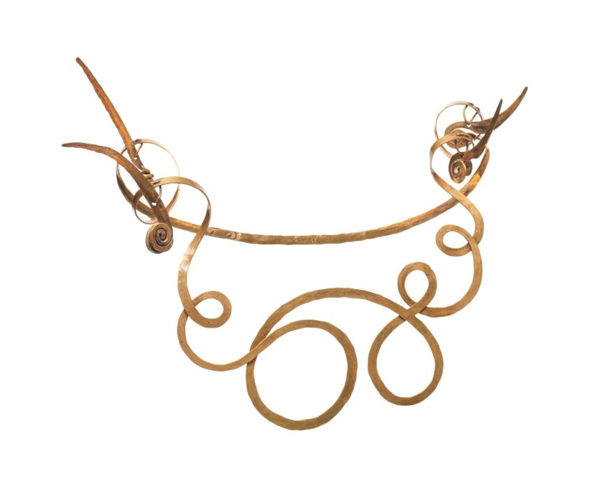 Ornate gold neck ring with intricate spirals and decorative curls against a white background.