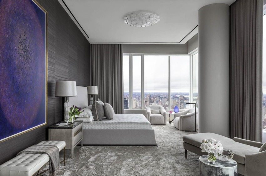 Modern bedroom with large windows, city view, abstract wall art, gray tones, and elegant furnishings.