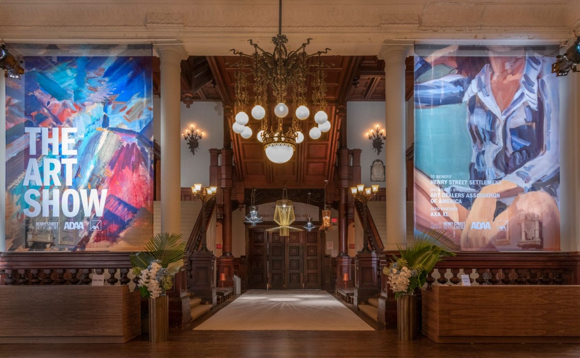 Entryway to an art exhibition with colorful abstract banners, elegant chandeliers, and ornate architectural details.