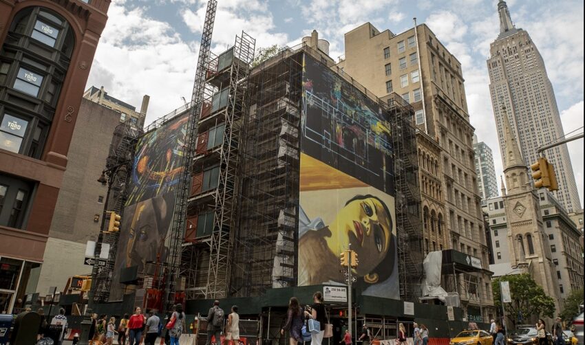 Scaffolding surrounds a building with large colorful murals in a city street, with people walking and tall buildings nearby.