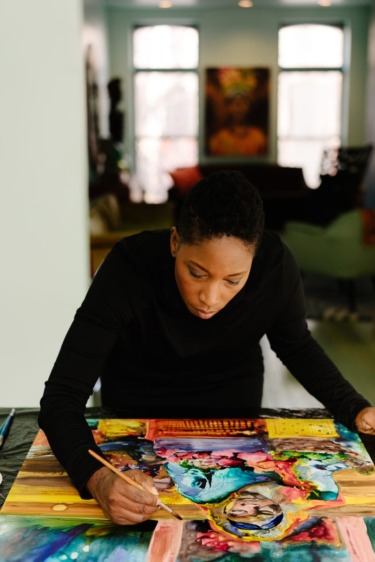 Artist focused on painting colorful artwork in a bright studio setting with soft lighting and creative ambiance