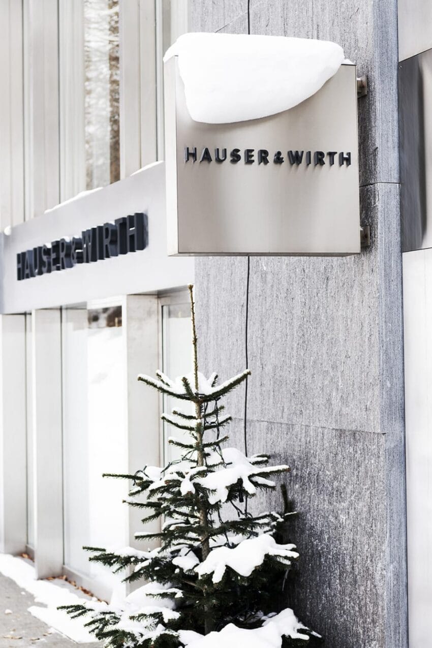 Snow-covered evergreen tree outside building with Hauser & Wirth signage.