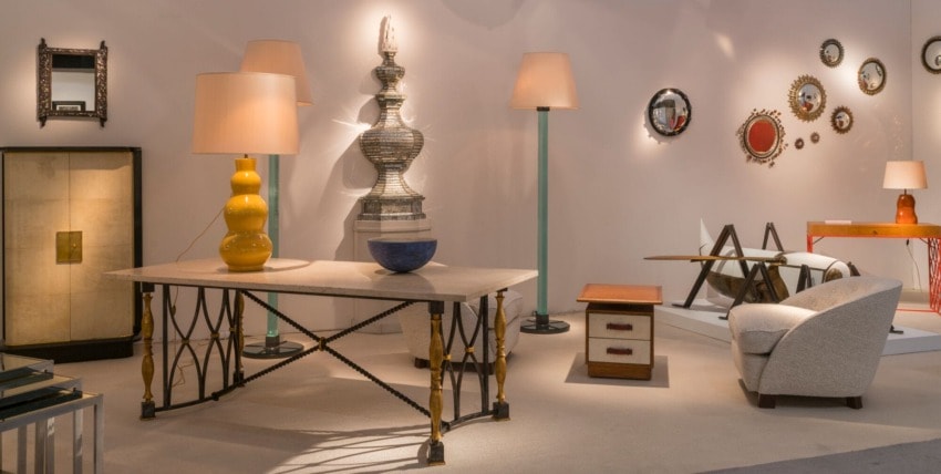 Room with eclectic furniture, including tables, lamps, mirrors, and a chair, showcasing modern and vintage design elements.