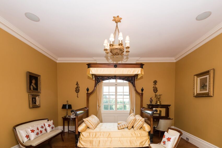 Elegant vintage bedroom with yellow walls, chandelier, canopy bed, and classic decor.