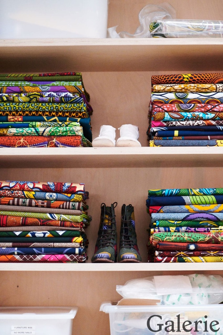 Shelves with colorful folded fabrics and baby shoes, showcasing vibrant textile patterns and children's footwear.