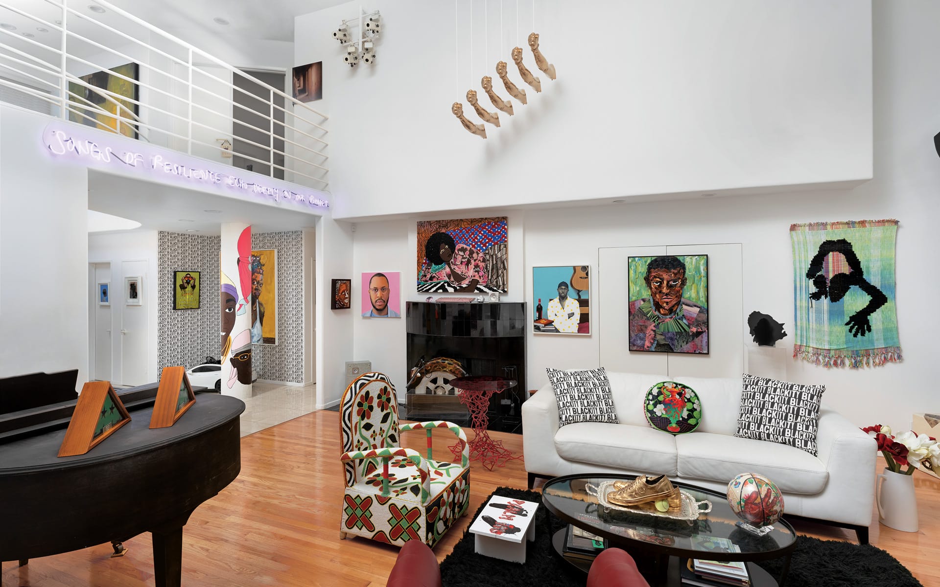 Stylish living room with modern art on walls, white sofas, piano, and unique lighting fixture hanging from high ceiling.