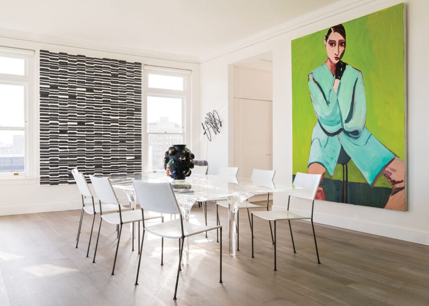 Modern dining room with white chairs, a glass table, abstract wall art, and a large colorful portrait on the wall.