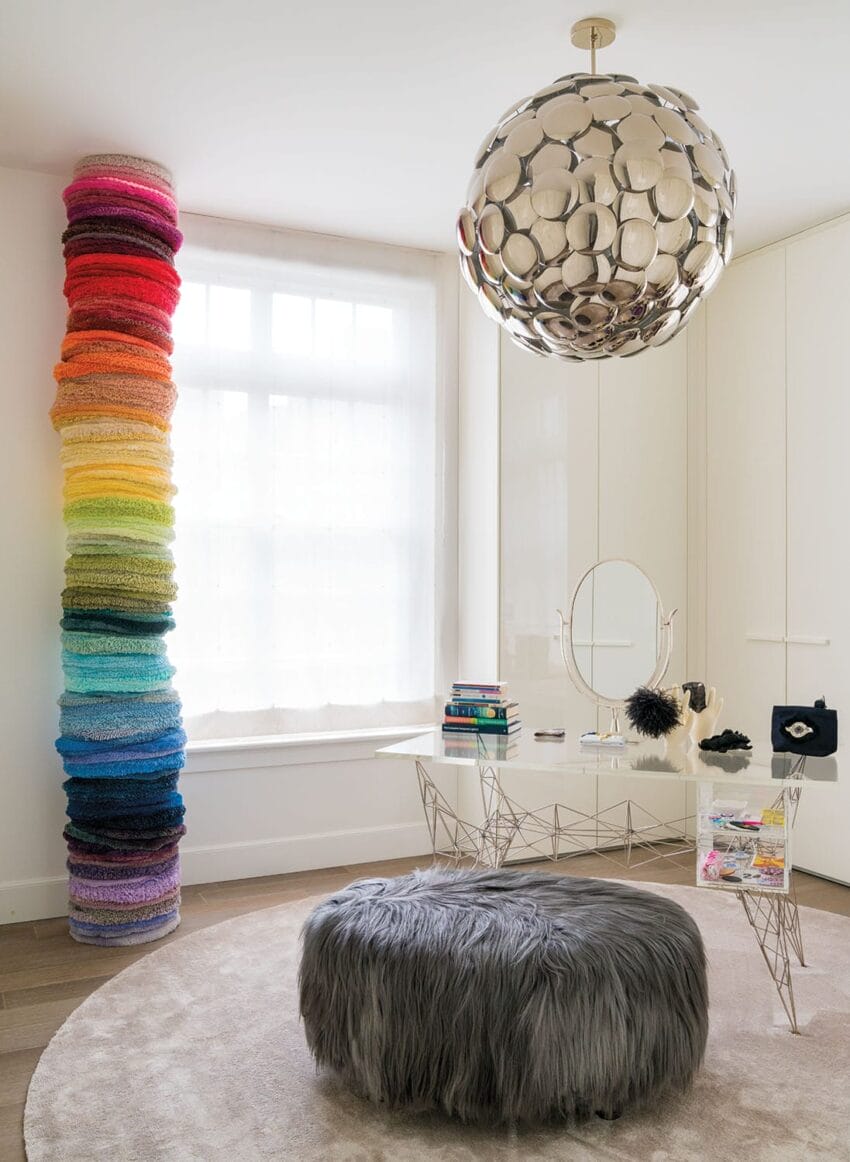 Colorful stacked yarn, modern chandelier, and stylish decor in a bright, contemporary room with a large window.
