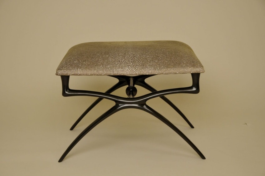 Modern artistic stool with metallic legs and a textured cushioned seat on a neutral background.