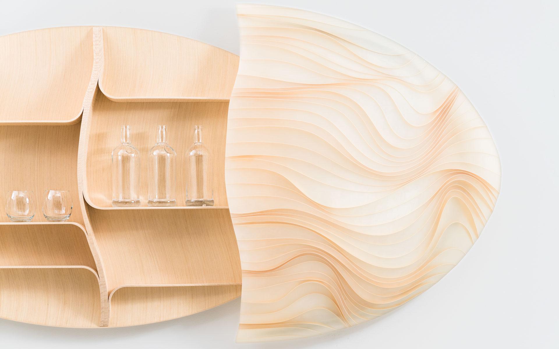 Wooden wall shelf with wavy design, holding clear bottles and glasses.