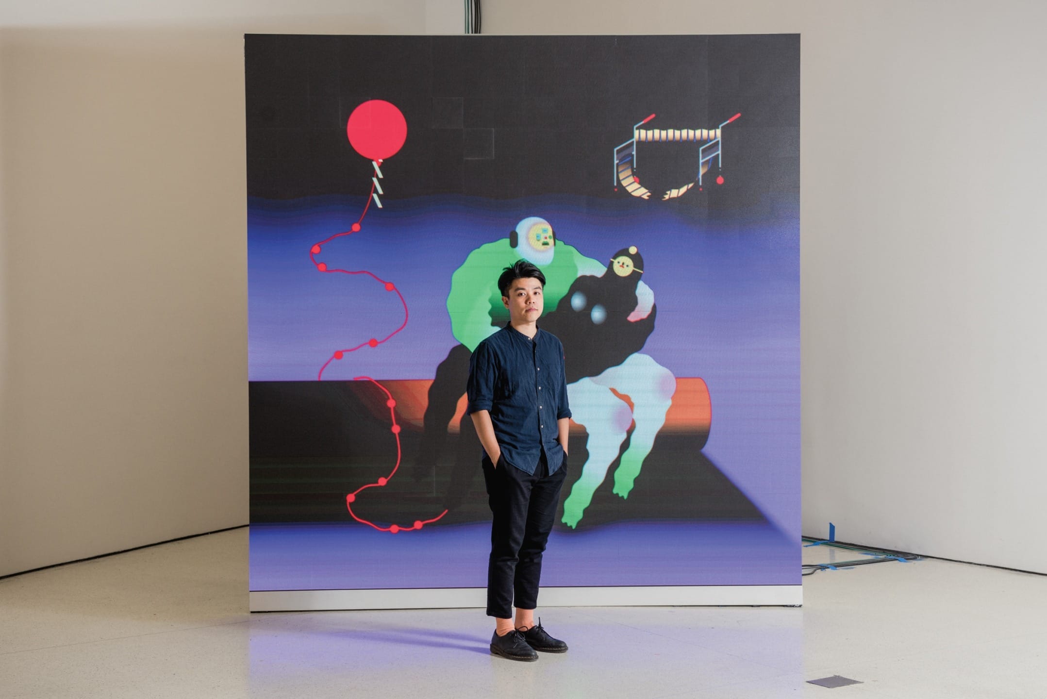 Person standing in front of a colorful abstract art piece featuring a red balloon and geometric shapes.
