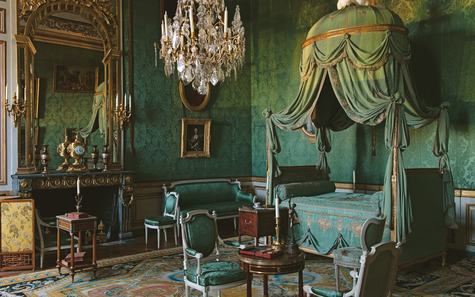 Luxurious vintage room with green drapes, ornate chandelier, period furniture, and an elegant canopy bed.
