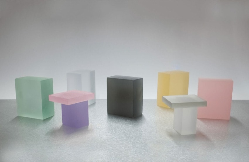 Colorful translucent blocks arranged in a row on a reflective surface, showcasing a modern minimalist style.