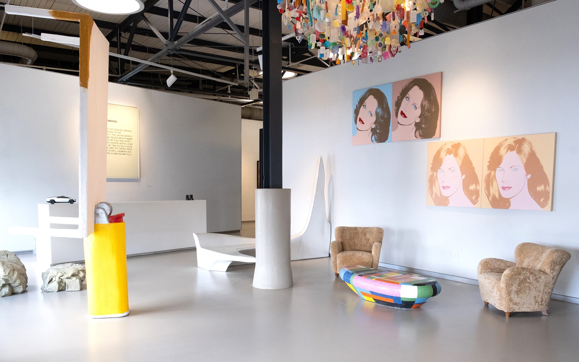 Contemporary art gallery interior with modern paintings, colorful chandelier, unique furniture, and abstract sculptures.