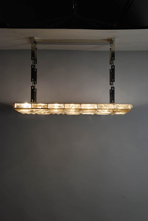 Modern rectangular chandelier with translucent stones hanging from a ceiling.