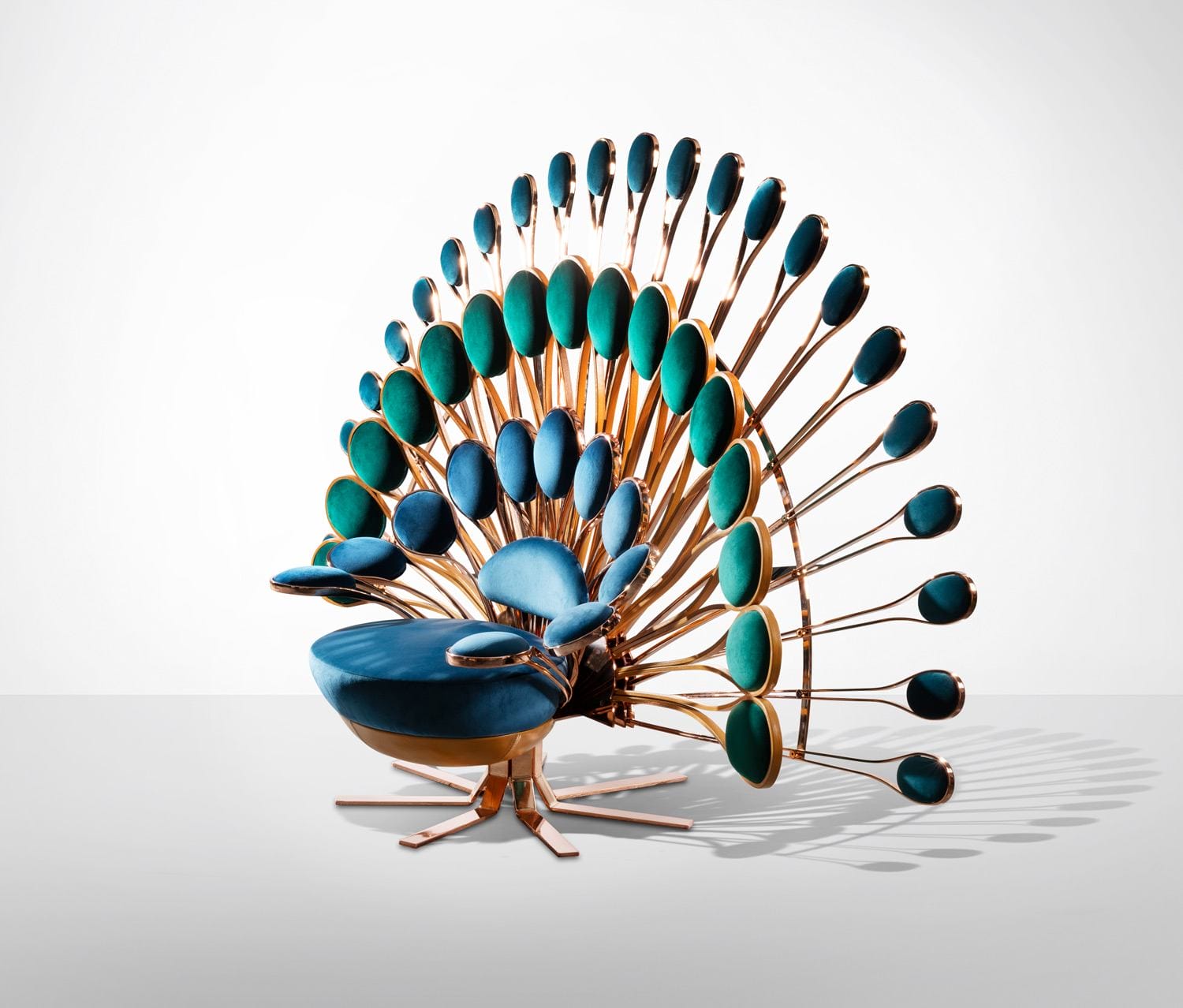 Unique peacock-inspired chair with vibrant blue and green feathers and intricate metallic frame on a white background.