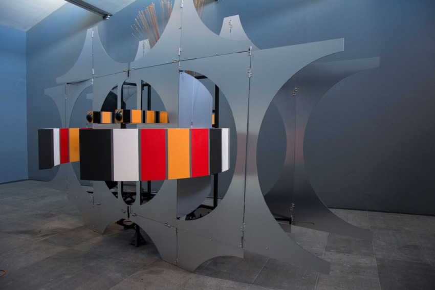 Modern art installation with colorful panels and metal framework in a gallery setting.