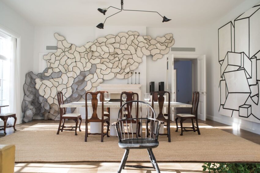 Modern dining room with abstract wall art, wooden chairs, minimalist table, and geometric carpet.
